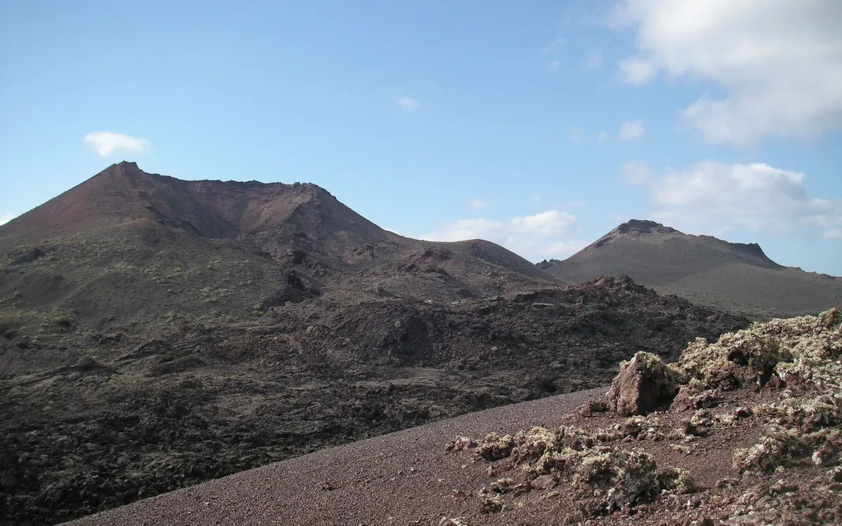 A guided group walking across a black lava field on Lanzarote