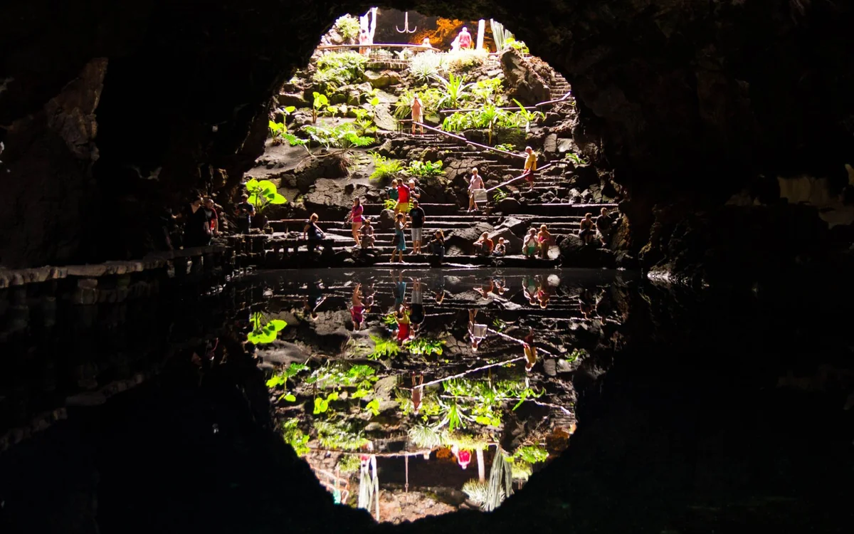 A lit walkway inside a lava cave on Lanzarote, with dark curved walls overhead