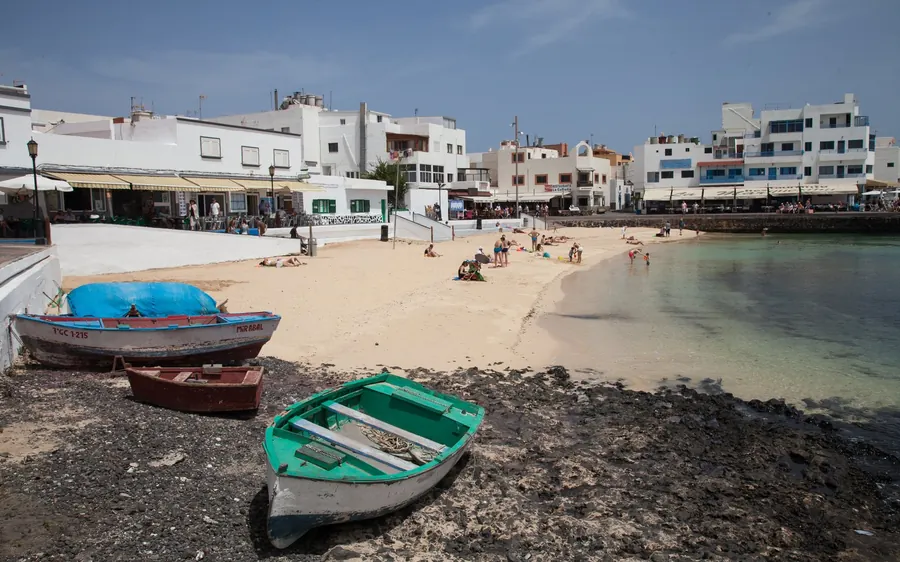 Painted fishing boats on the shore in front of a whitewashed seaside village