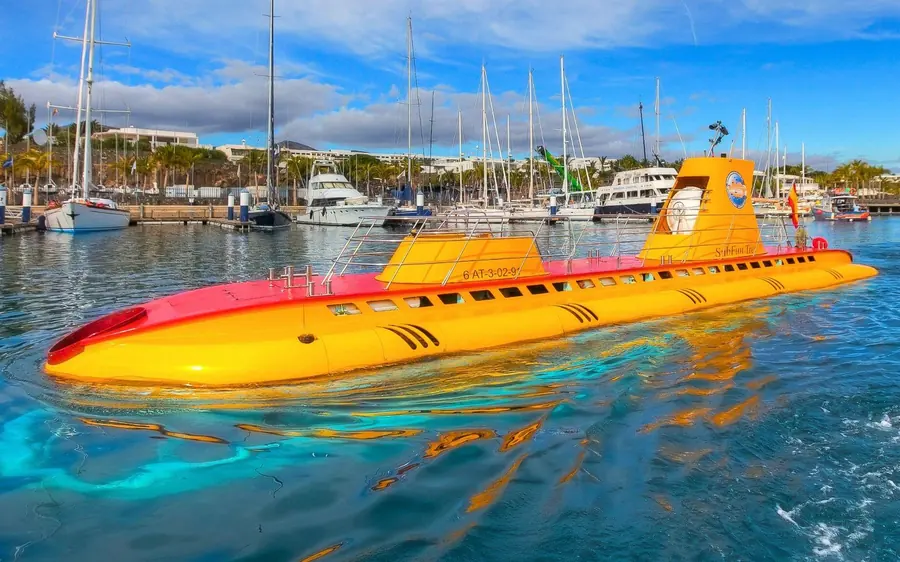 A yellow passenger submarine floating in a marina beside moored yachts